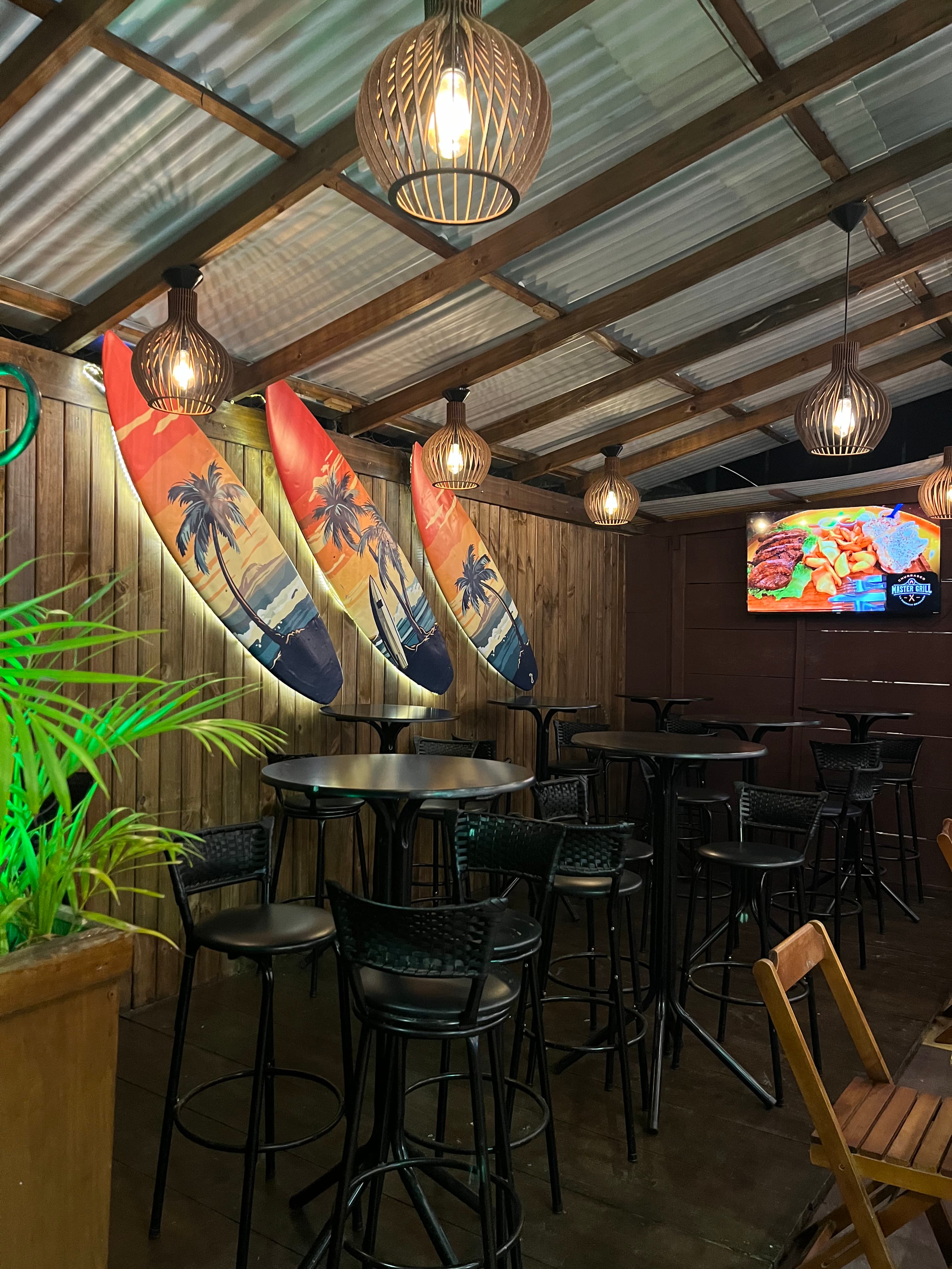 Área interna com decoração surf e mesas altas